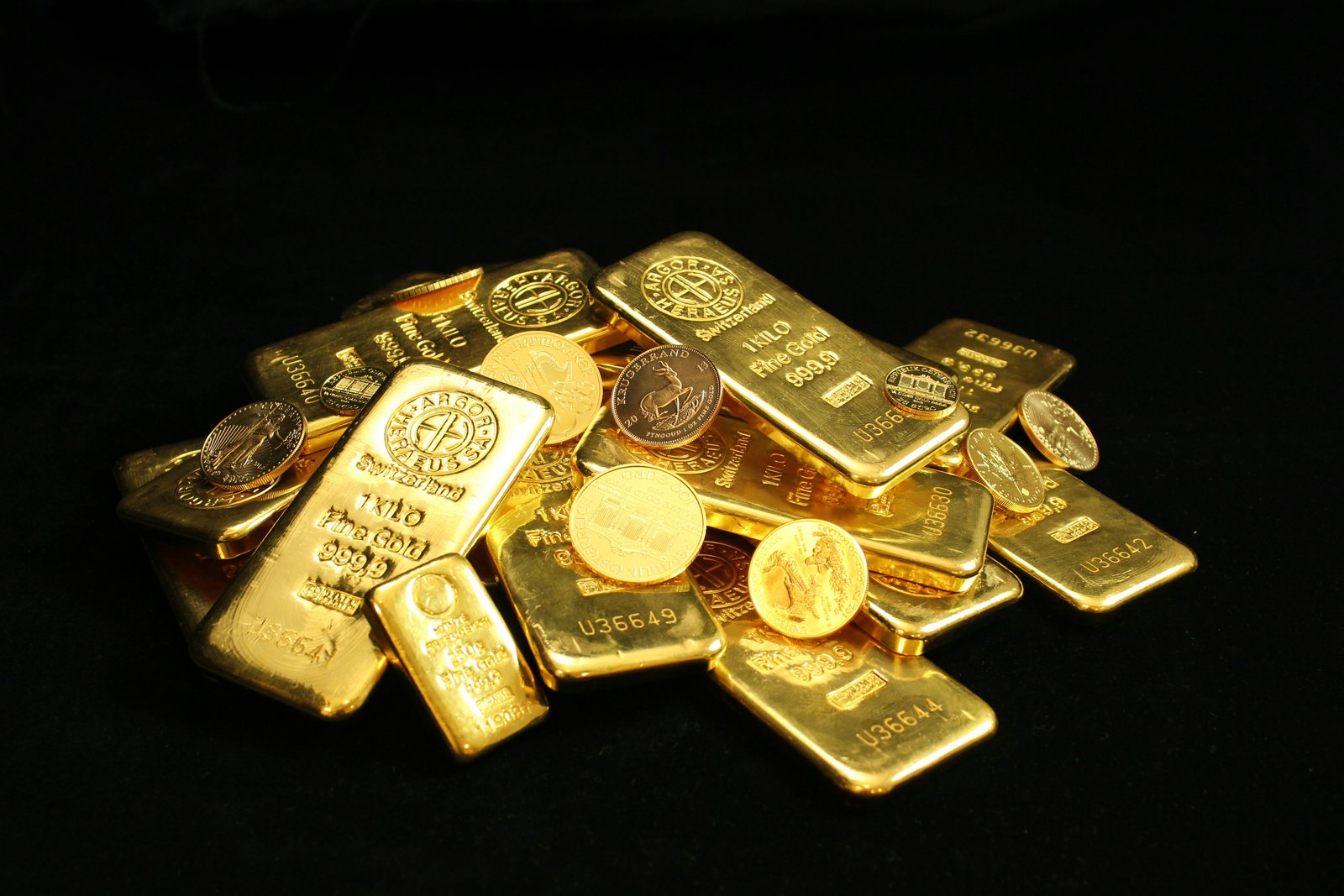 Gold bars and bullion coins against a black background