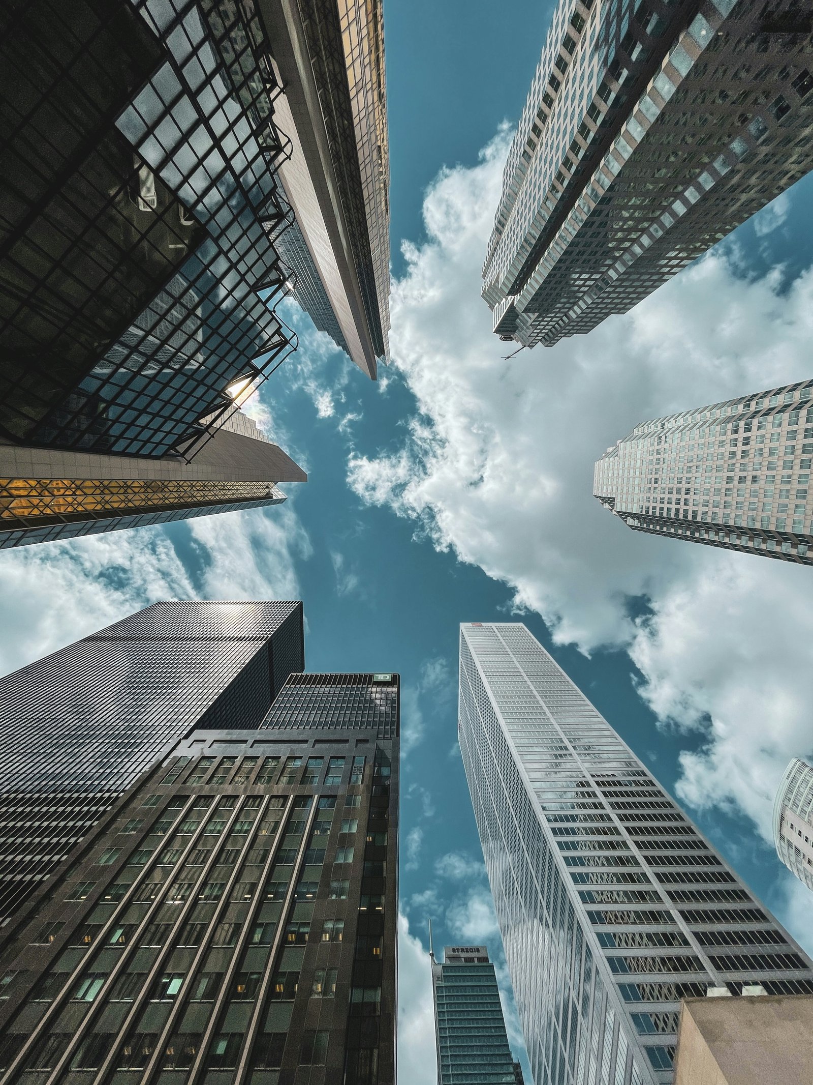 Looking up between skyscrapers toward an open blue sky